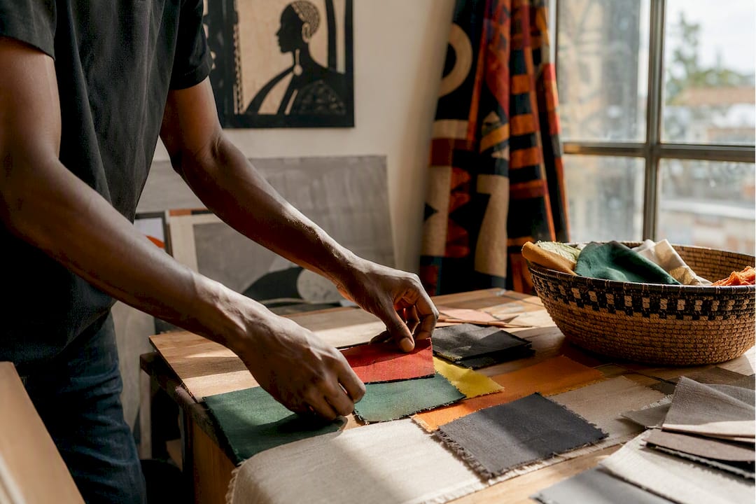 Hands arranging Pan-African color fabric swatches